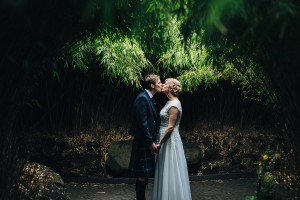 Bride and groom kissing under trees Alnwick Gardens