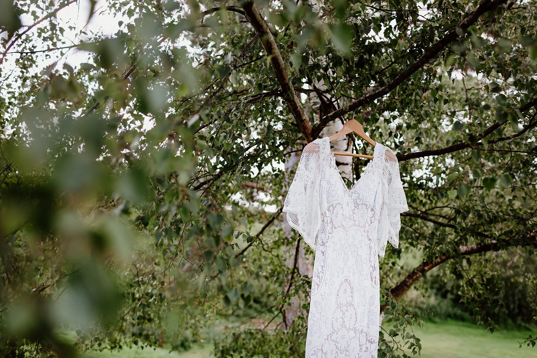 White crochet boho wedding dress hung outside from a tree at Camp Katur