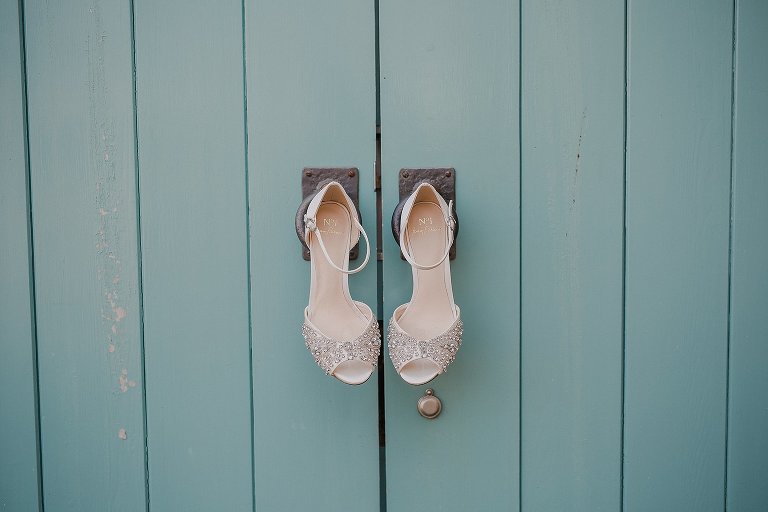 Bridal wedding shoes hung on blue door