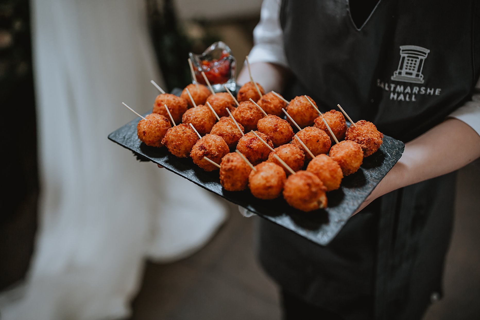 Wedding canapes being served at Saltmarshe Hall. Canapes look like arancini balls and are laid on a black slate board.