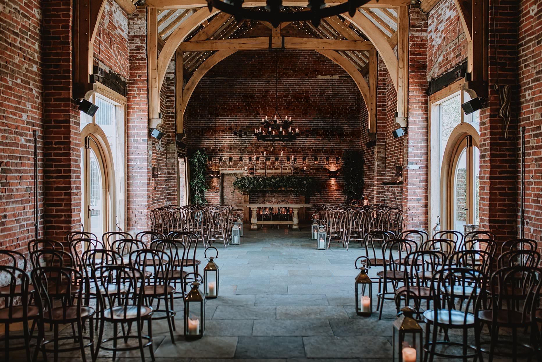 Interior of the ceremony room at Hazel Gap Barn. Exposed brick walls and wooden beams the room is decorated with candles.