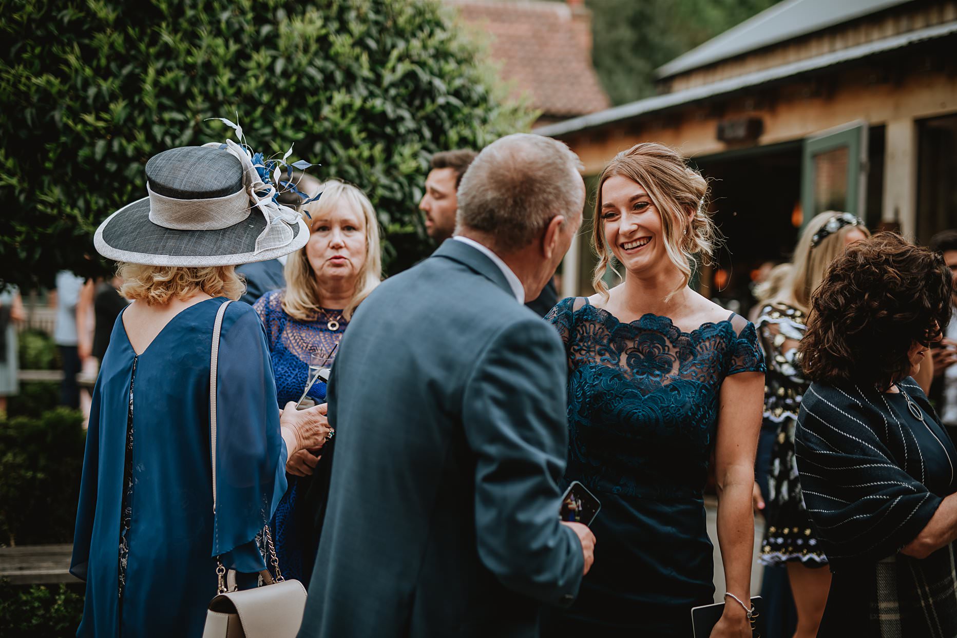 Bridesmaid chatting to other wedding guests in the courtyard at Hazel Gap Barn.