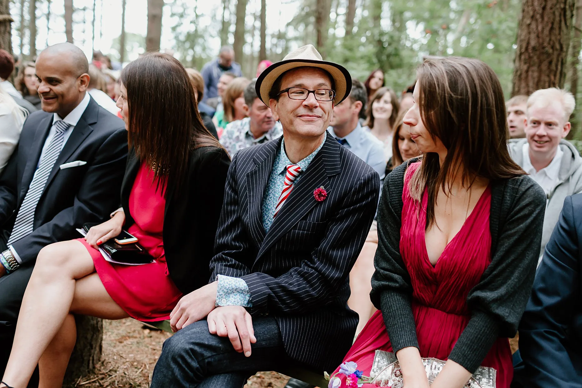 Wedding guests sat outside woodland chapel at camp katur waiting for the bride