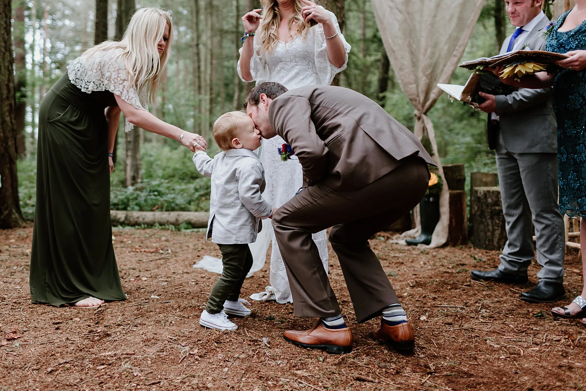 Groom leaning in for a kiss with his nephew. His nephews face is all scrunched up and looks very cute.