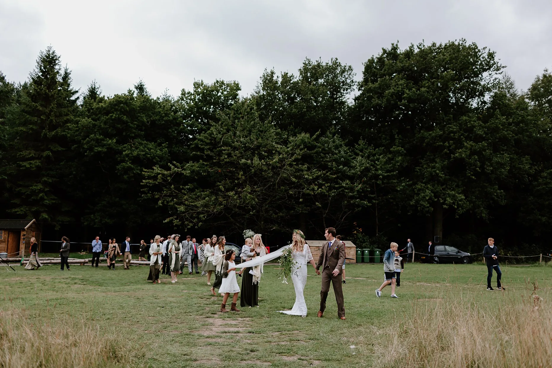 Bride and groom lead wedding guests to the meadow at Camp Katur for the drinks reception.
