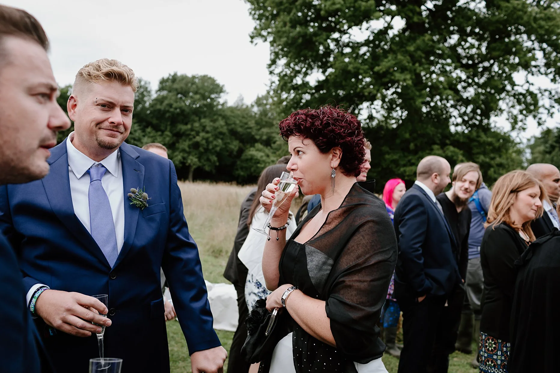 Wedding guests drinking champagne in the meadow at Camp Katur during the drinks reception