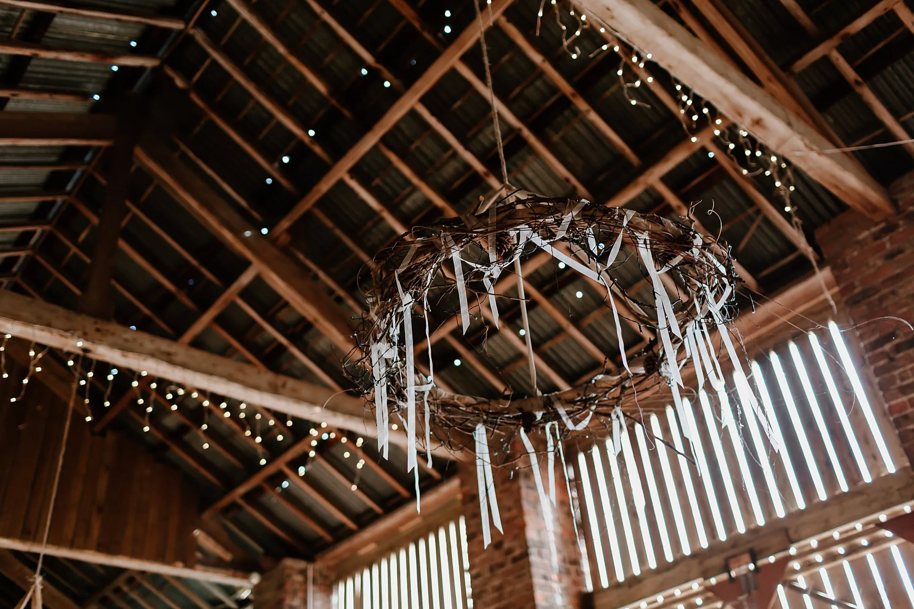 A wicker hoop hung from the wooden beams inside a wedding barn at Camp Katur.