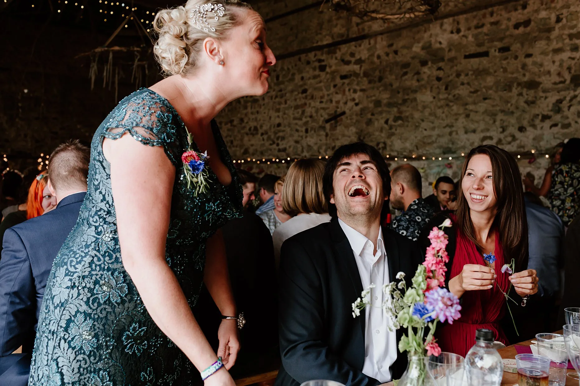 Three wedding guests laughing and being silly during wedding breakfast.
