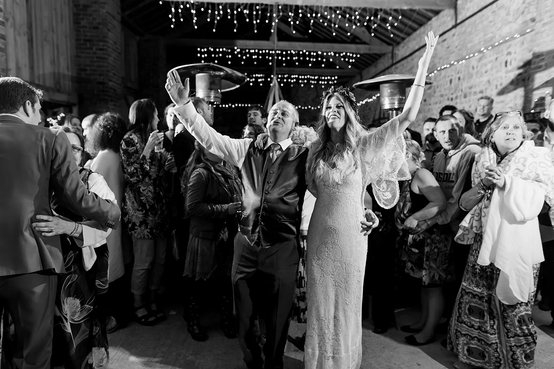 Bride dancing with her dad on the evening of her wedding. Both bride and dad have there hands thrown in the air enjoying the music.
