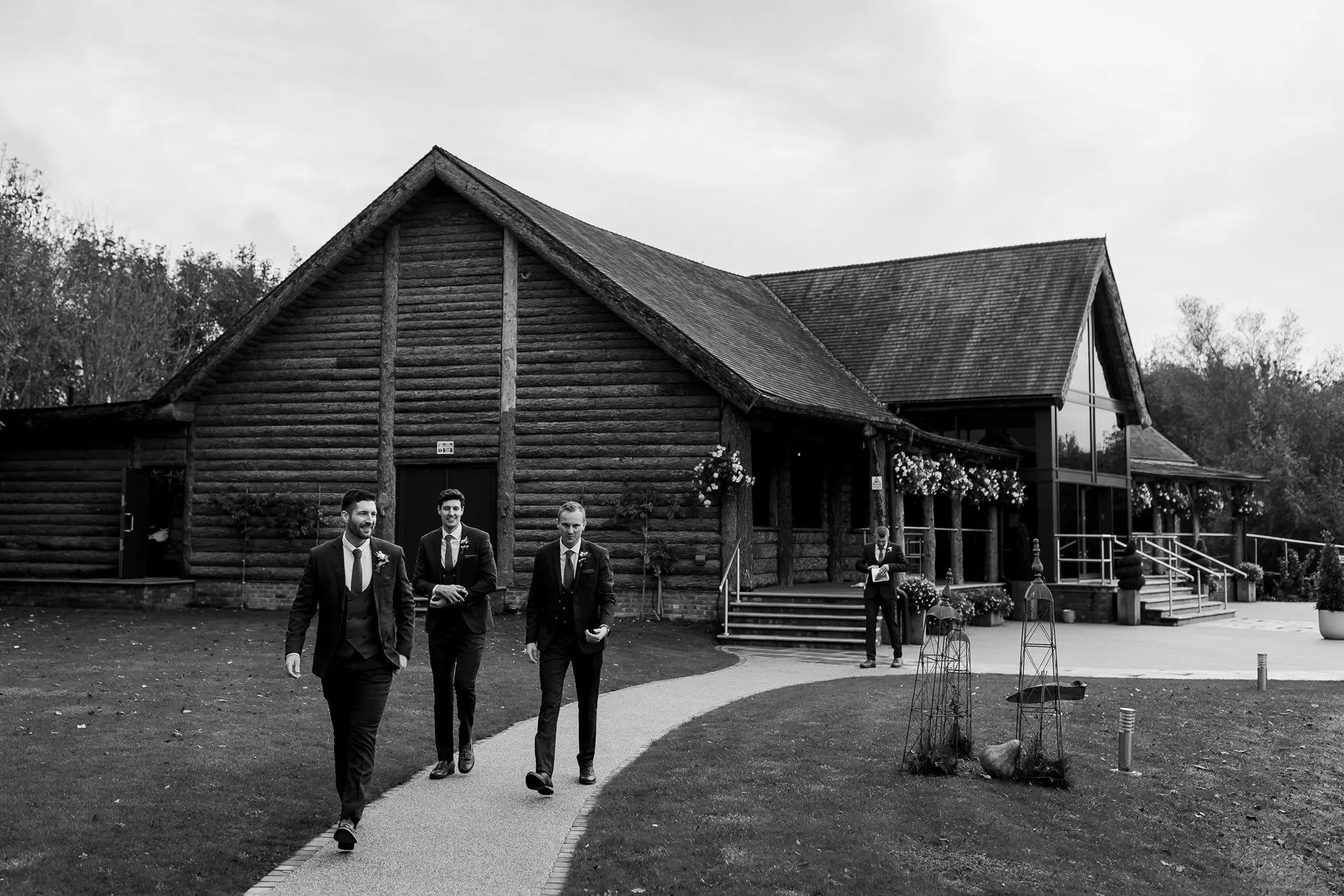 Groom walking with his groomsmen to the wedding ceremony. The grand lodge at Oaklands can be seen in the background.