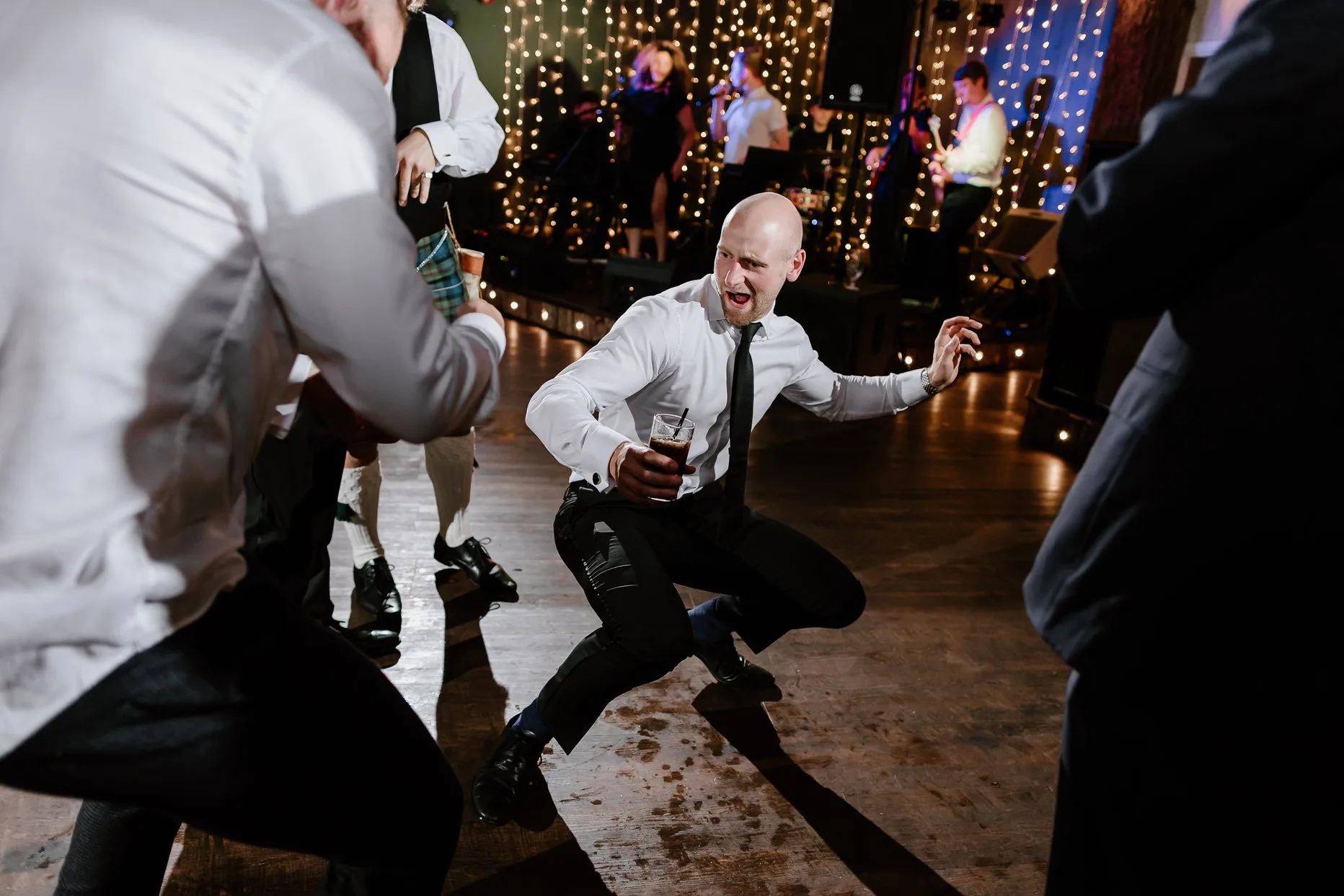 Wedding guest dancing on dancefloor at Oaklands. He is crouched down making a silly face.