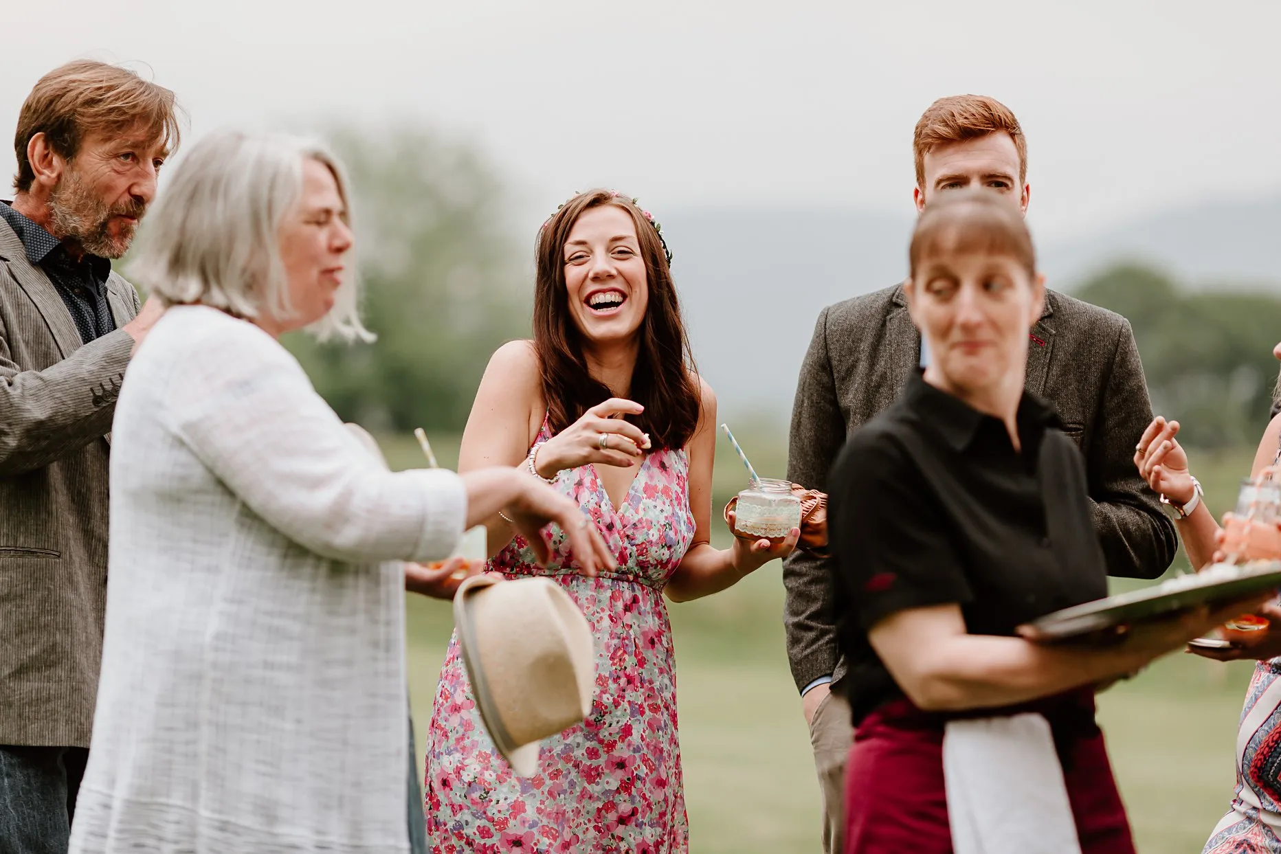Natural photograph of wedding guests laughing and smiling during the drinks reception at New House Farm in Lorton Valley, Lake District.