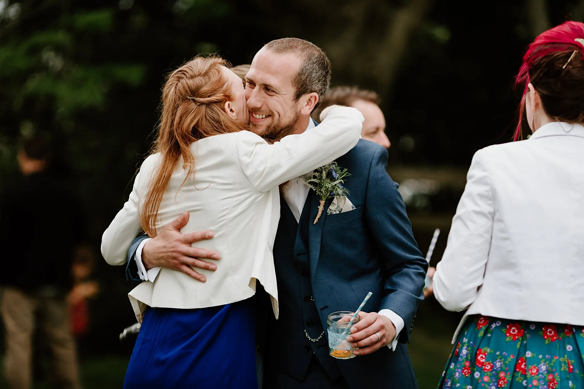 Natural photo of the Groom hugging a wedding guest and smiling during the drinks reception.