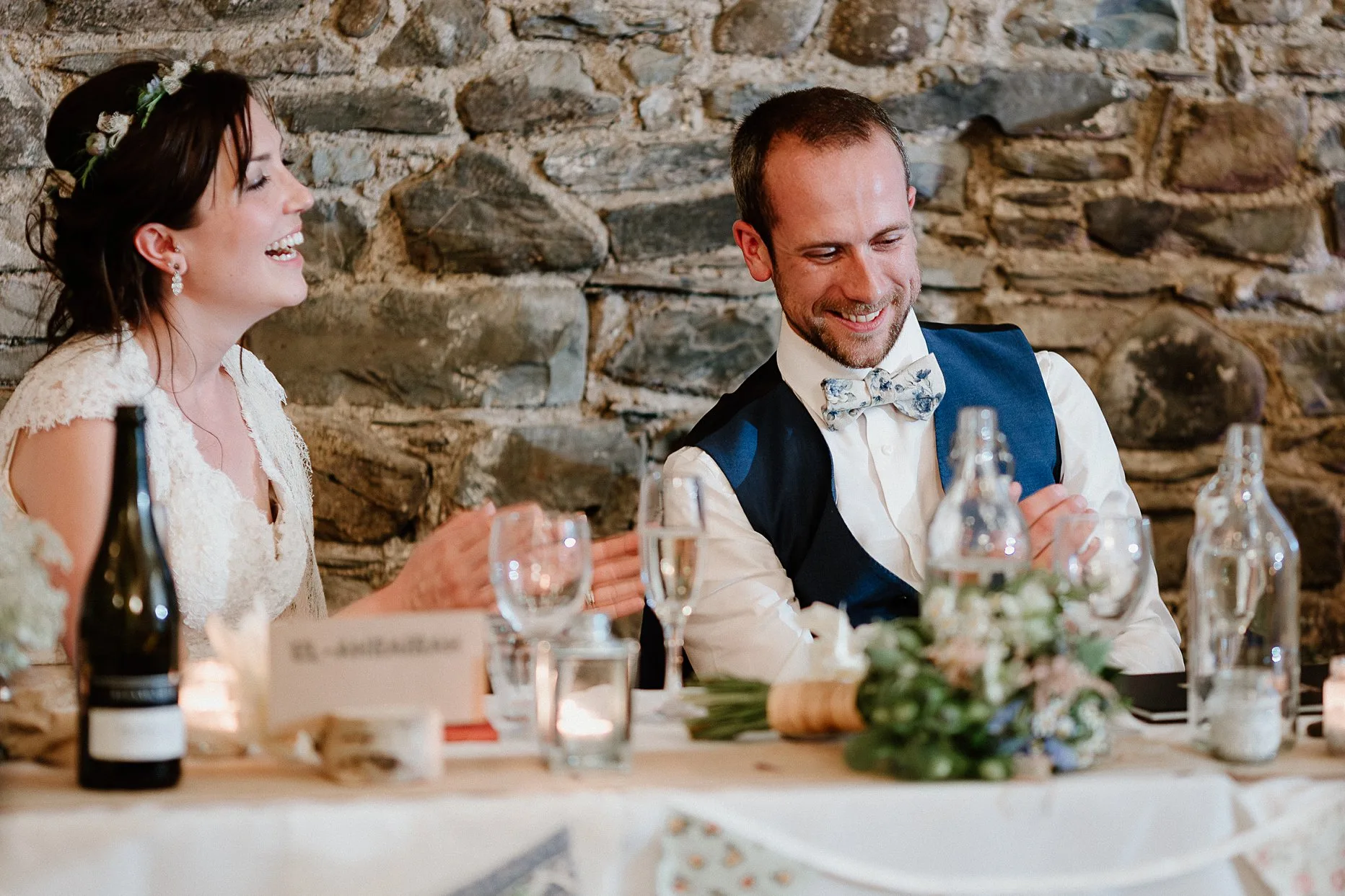 Natural photo of bride and groom laughing during wedding speeches at New House Farm wedding barn.