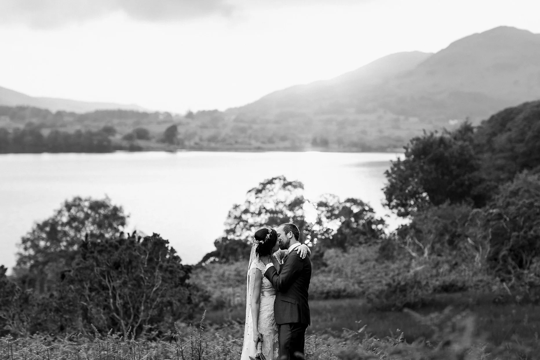 Bride and groom sharing a kiss at sunset with Crummock water in the background. 